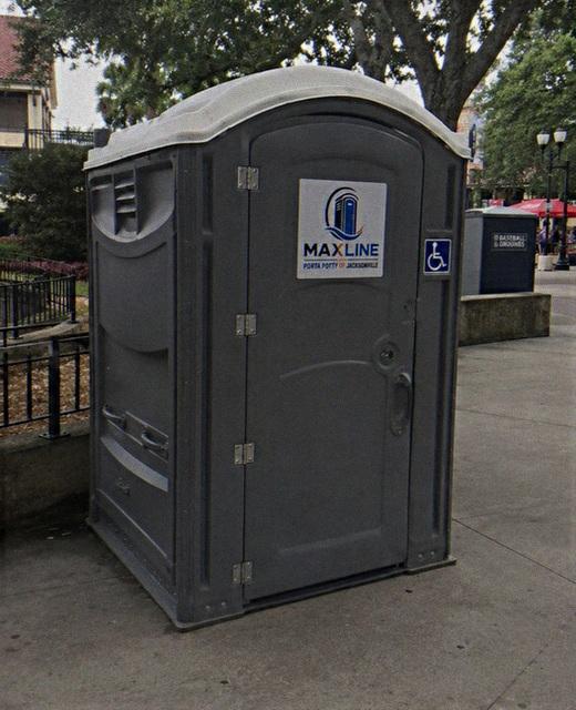 ADA-accessible portable toilet in a shaded park setting
