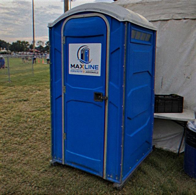 Maxline portable toilet positioned at an outdoor event beside a catering tent