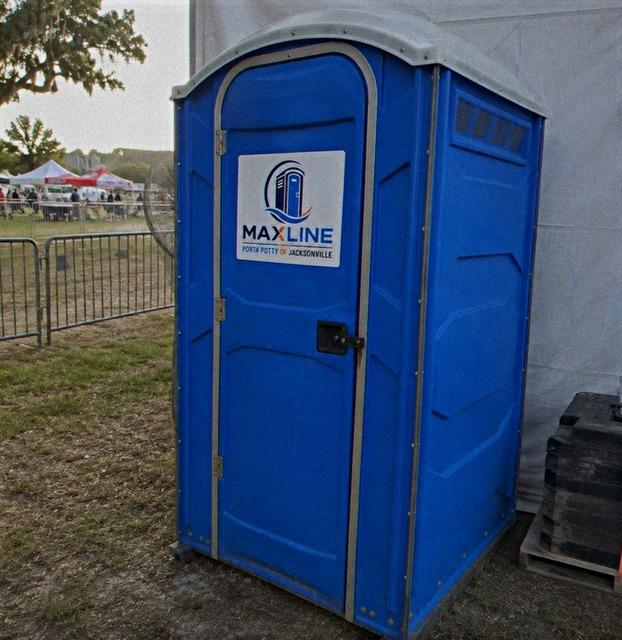 Row of Maxline portable toilets behind crowd barriers at a festival