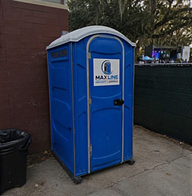 Portable toilet positioned near an outdoor concert stage