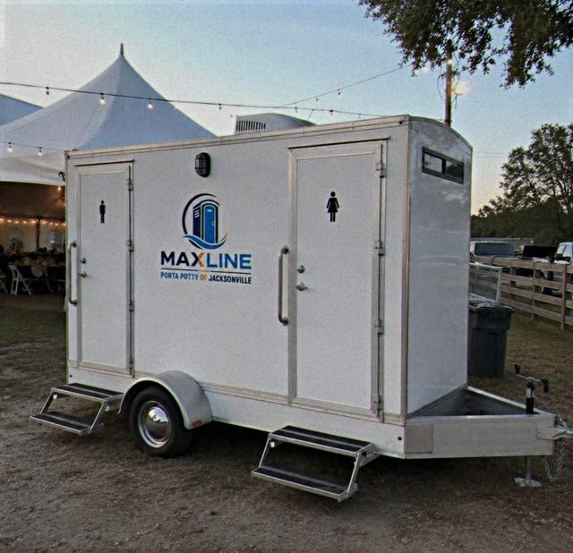 Two-stall restroom trailer parked beside a wedding marquee